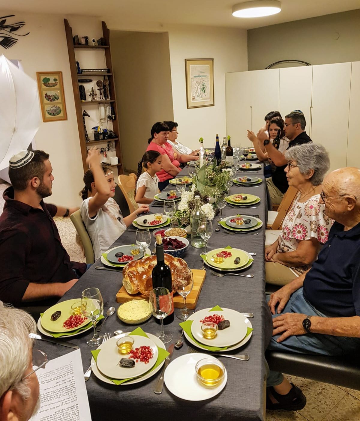 Das Foto zeigt Familie und Freunde beim Neujahrsmahl mit Granatäpfelkernen, Honig, Datteln und dem süßen Hefezopf Challa.. (Wird bei Klick vergrößert)